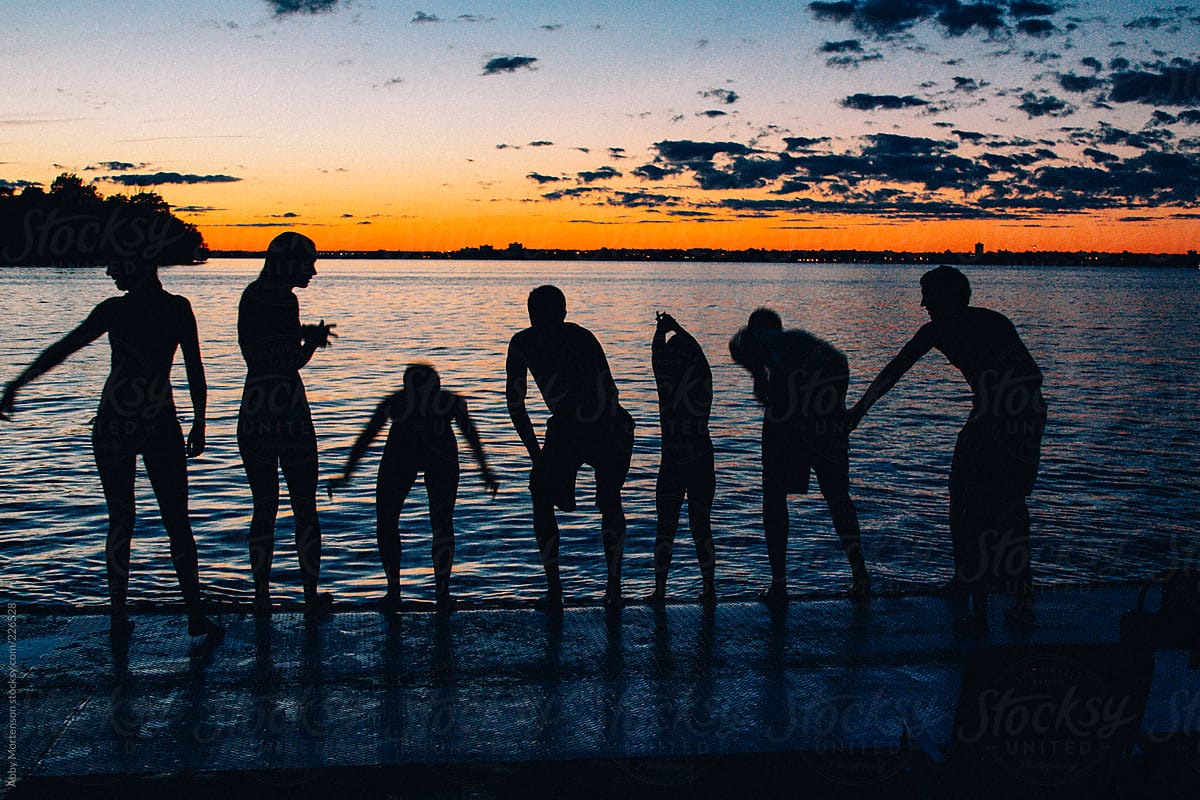Silhouette of People about to jump in water at sunset