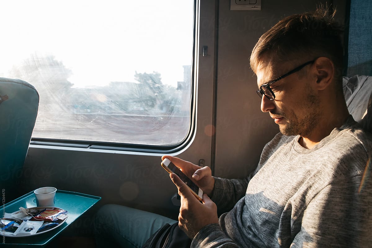 Young male riding on train using cell mobile phone technology