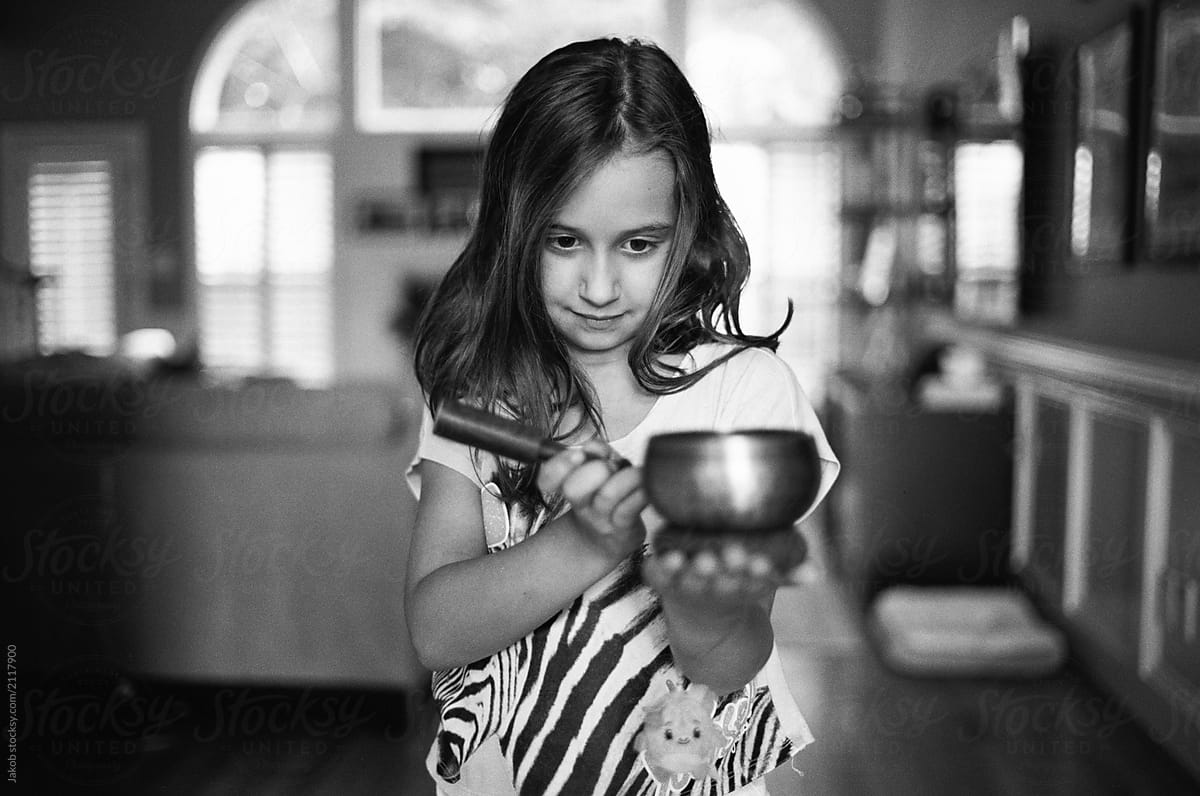 Cute young girl striking a meditation bell