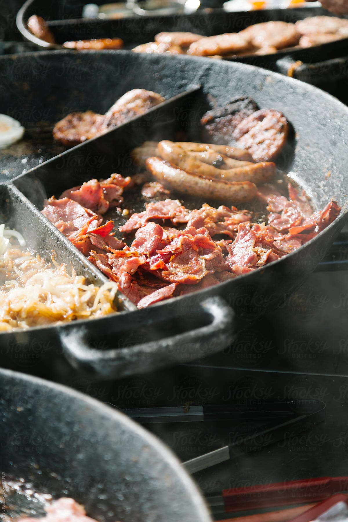 Bacaon, sausages, burgers and onion frying at market stall