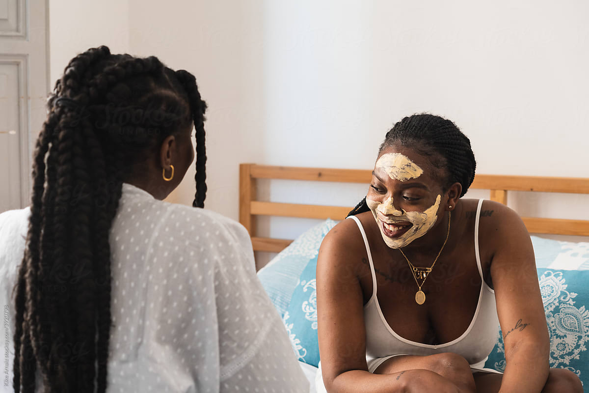 Laughing women with face mask on bed