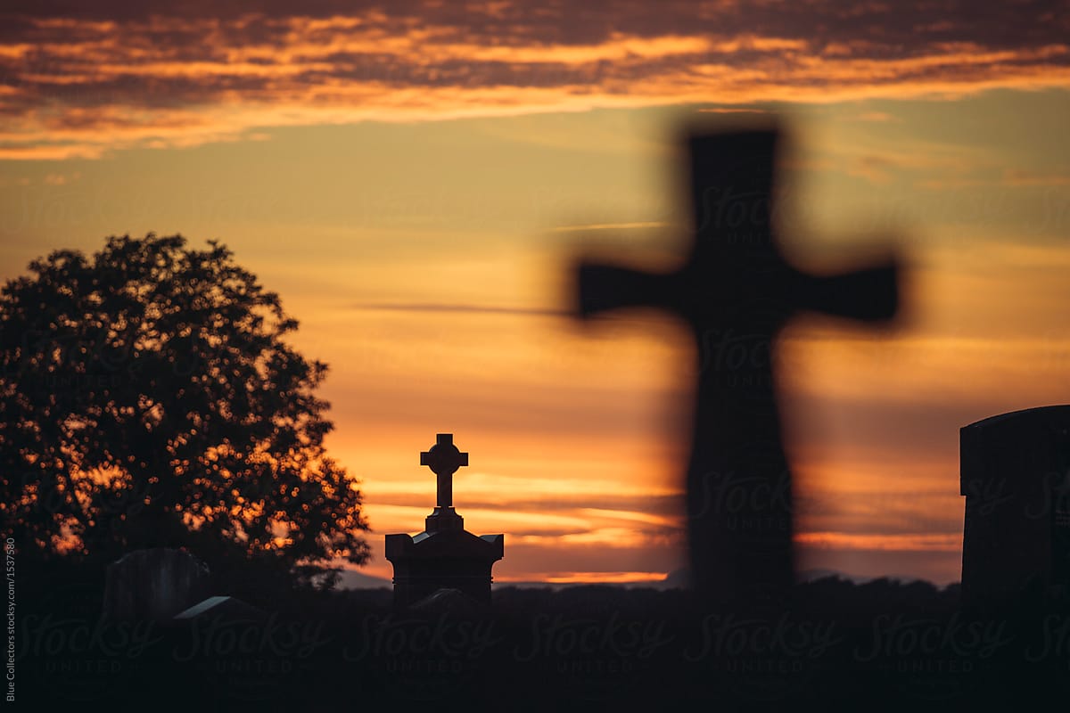 view of a red sunset with silhouettes of crosses from a cemetery
