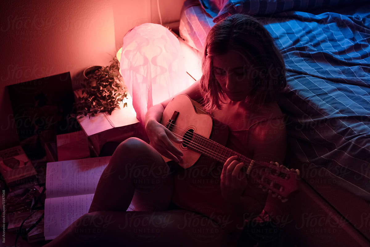 Relaxed woman learning with small guitar in bedroom