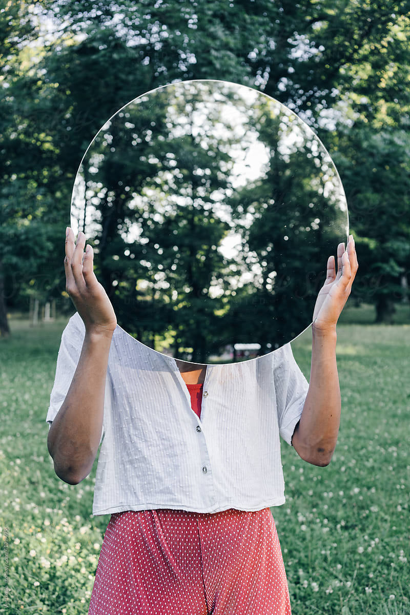 Conceptual portrait of a woman with mirror in park
