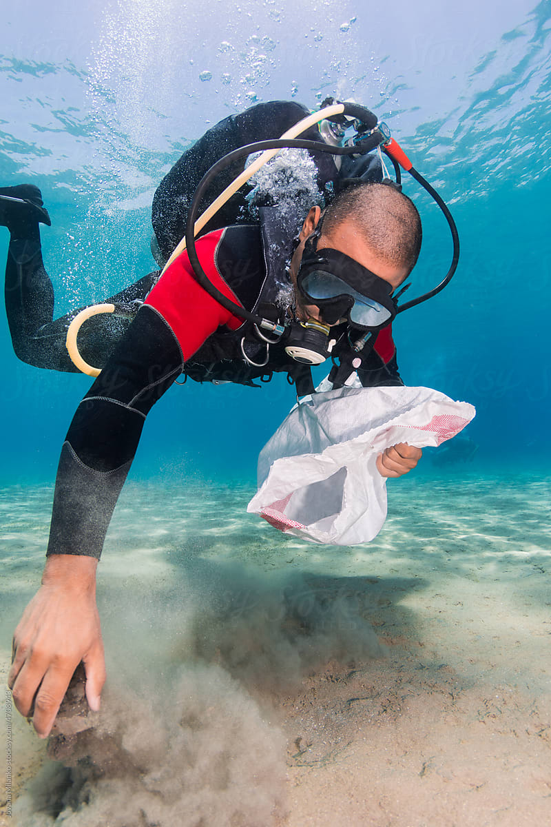 Scuba Diver Man Picking Up Plastic from the Ocean Sea Floor