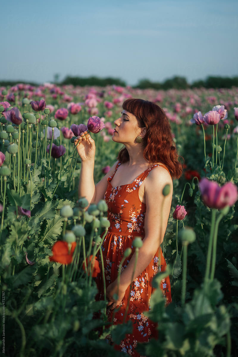 Portrait Of A Redhead Woman In The Field Smelling Flowers