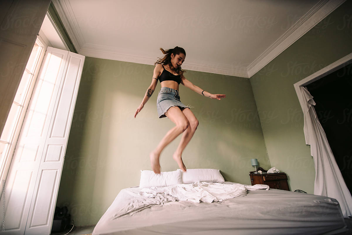 Woman jumping on bed
