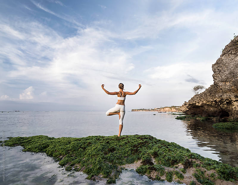 woman practicing yoga at sea shore