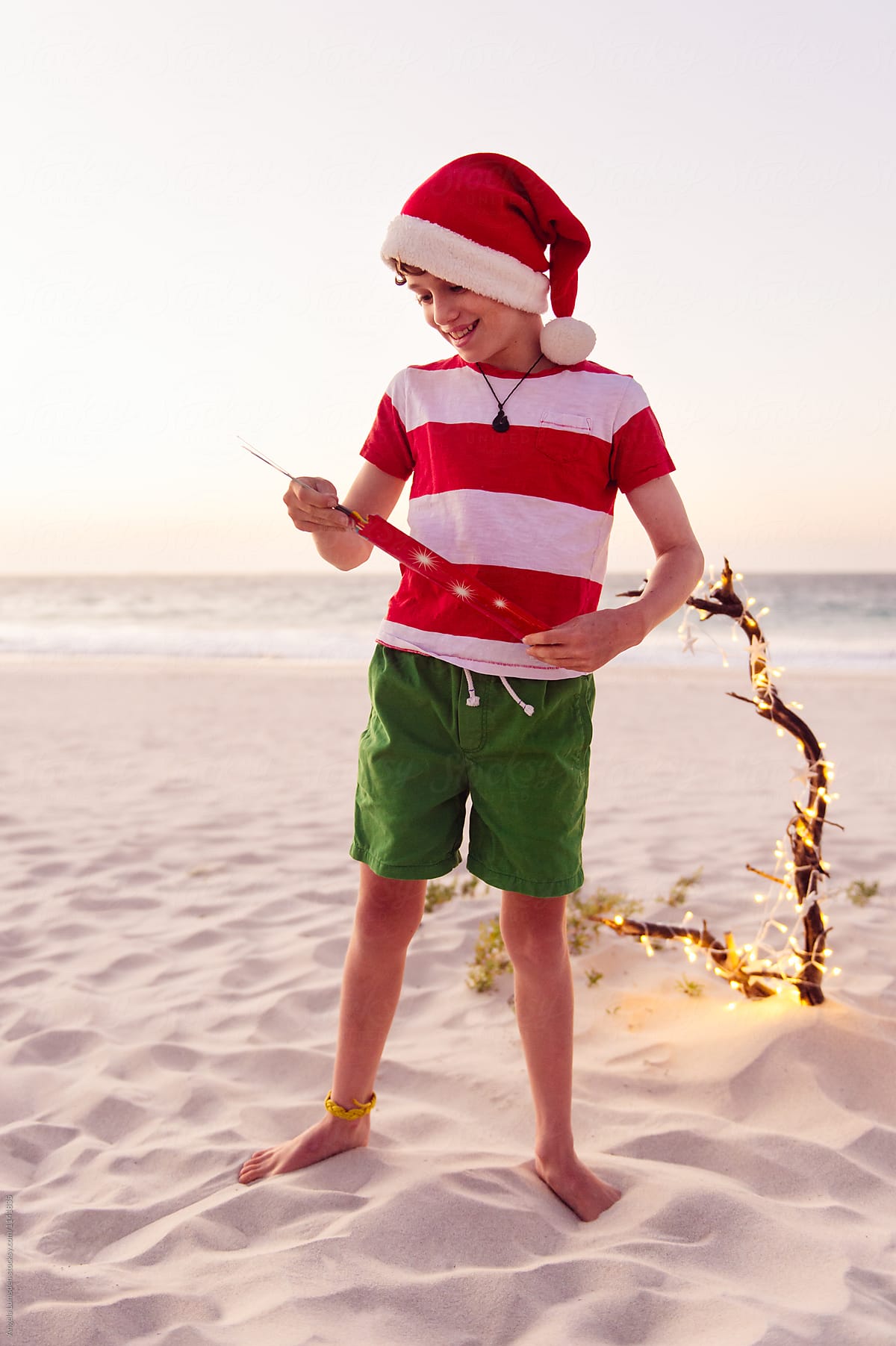 Boy playing with sparklers at the beach at sunset