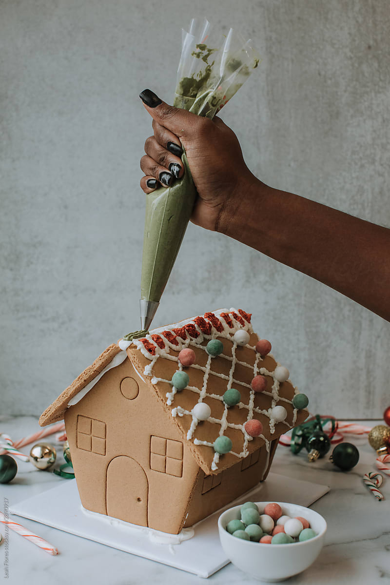 Woman Putting Icing on Holiday Gingerbread House