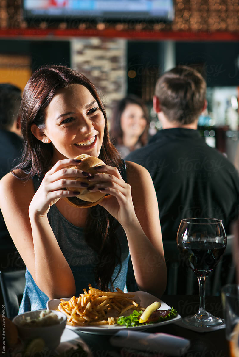 Bar: Woman Eating Hamburger Laughs With Friends