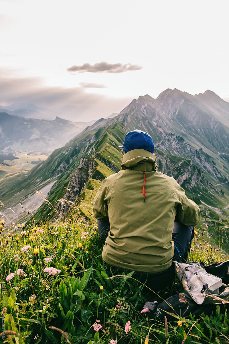 Faceless Male Hiker Sitting in Grass And Watching Sunrise in Mountains