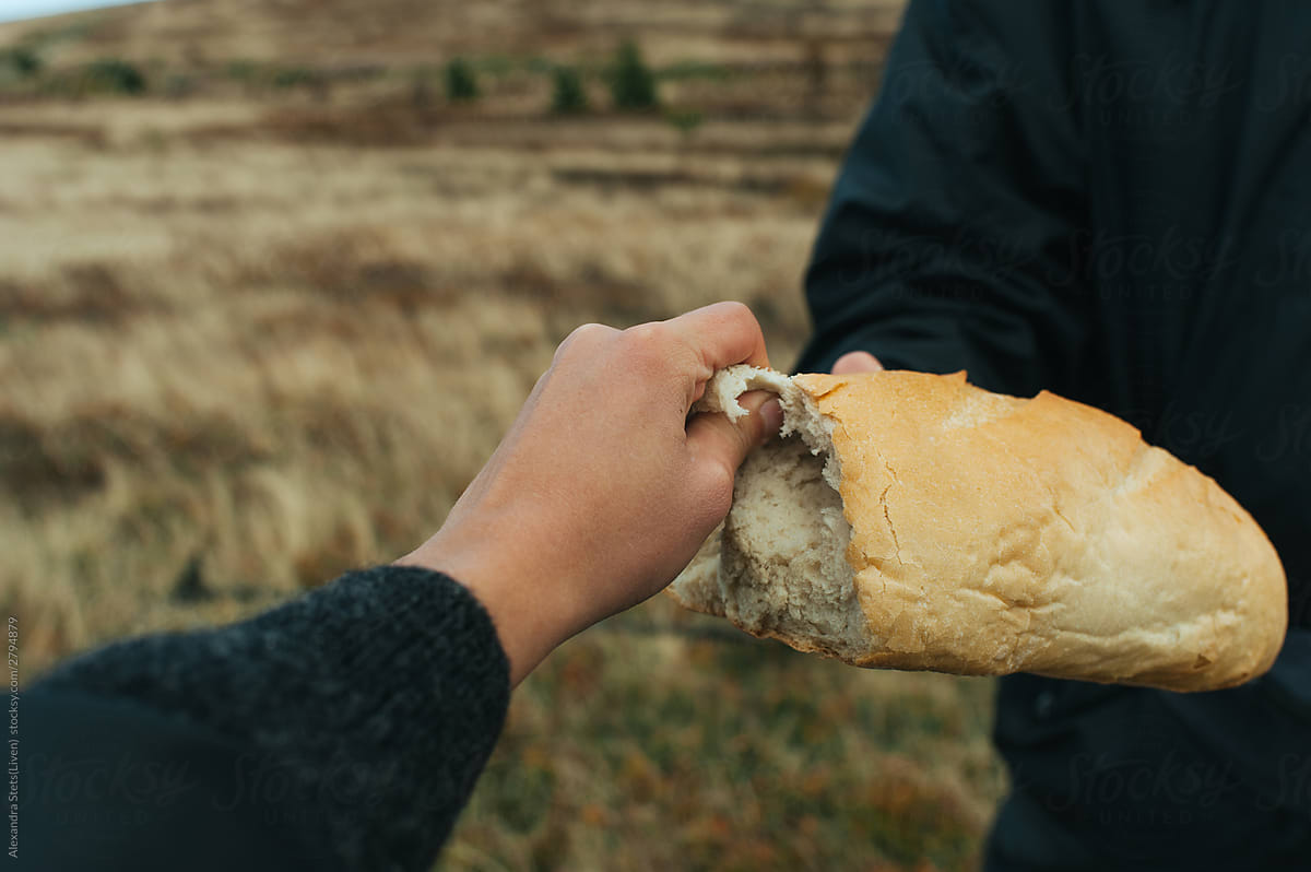 Hand tears off a piece of bread in the mountains.