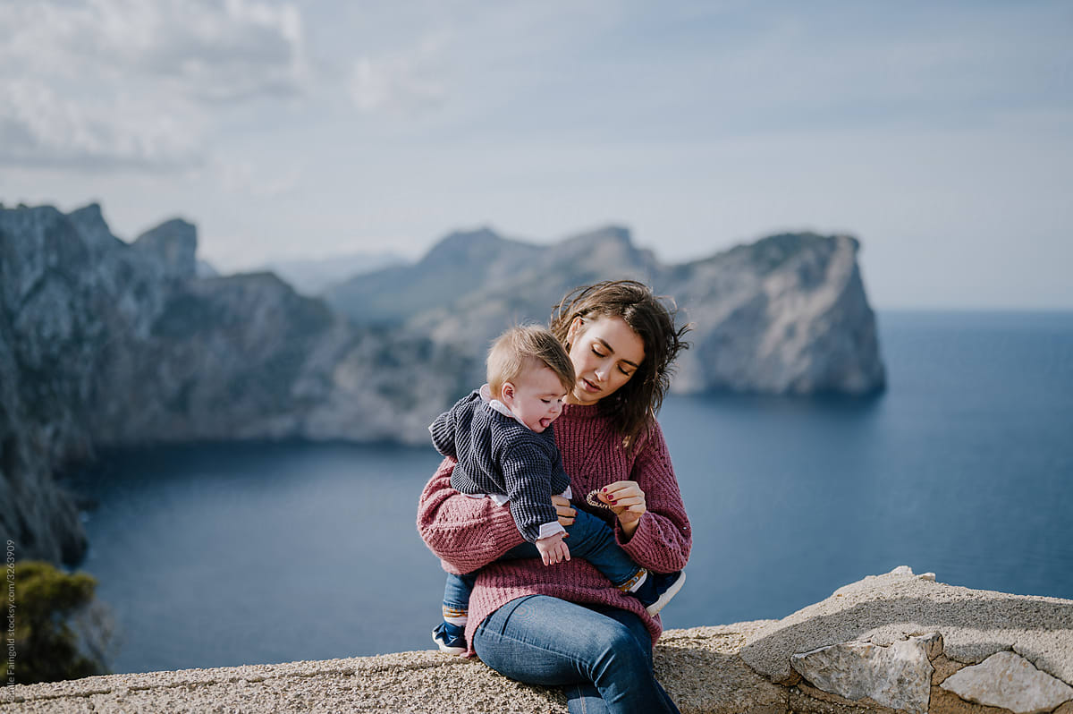 Mother with baby against sea and cliffs