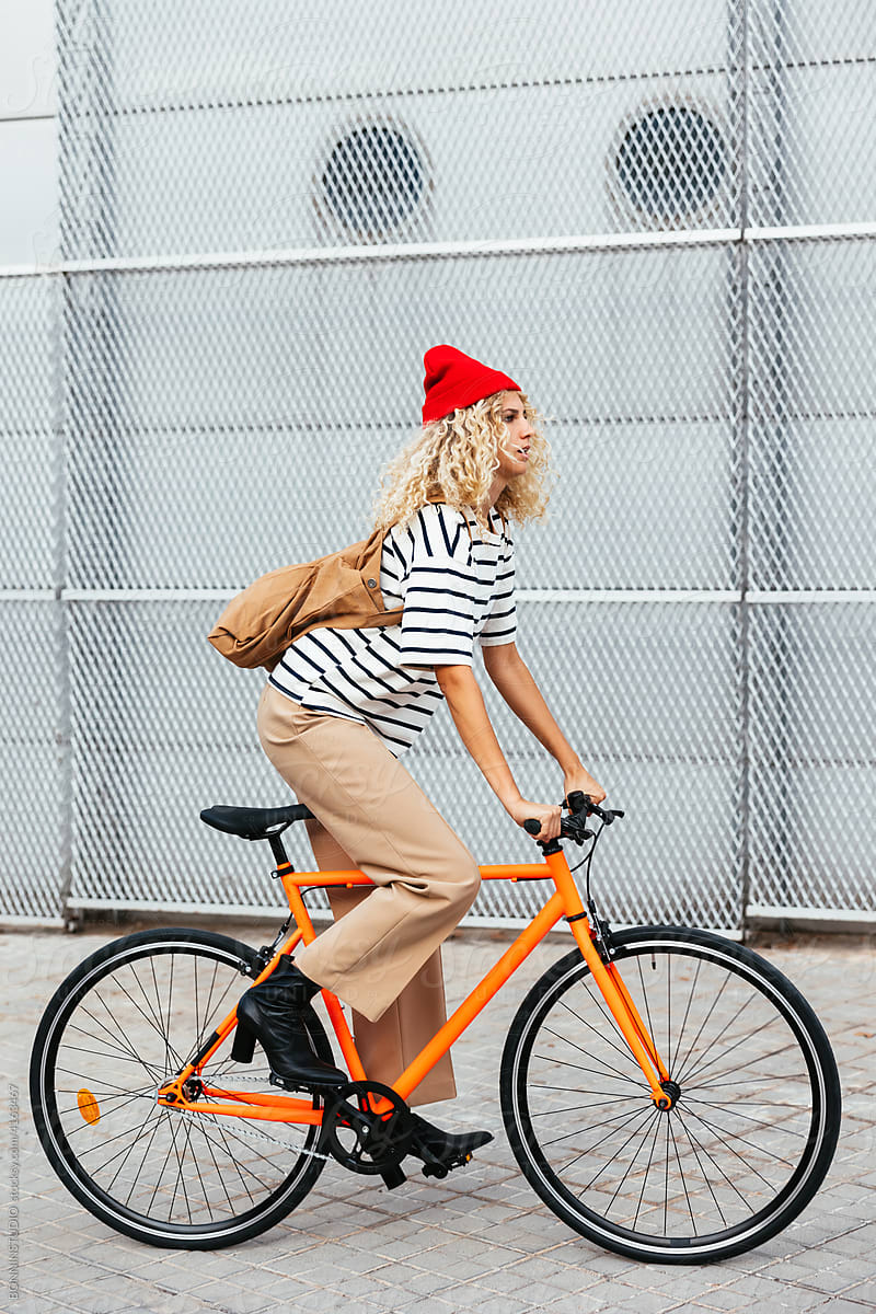 Stylish woman riding bike on street