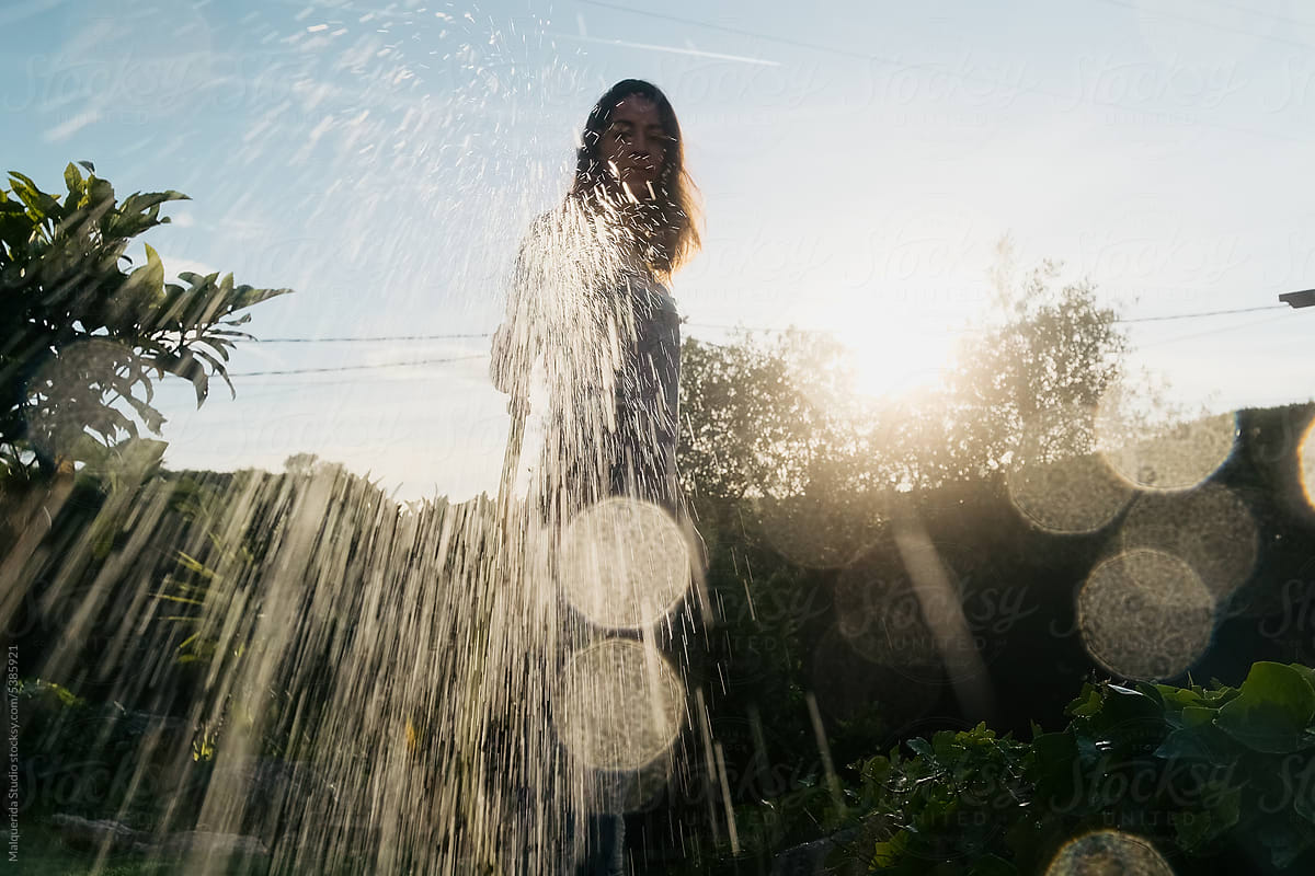 Woman watering to the camera with a hose