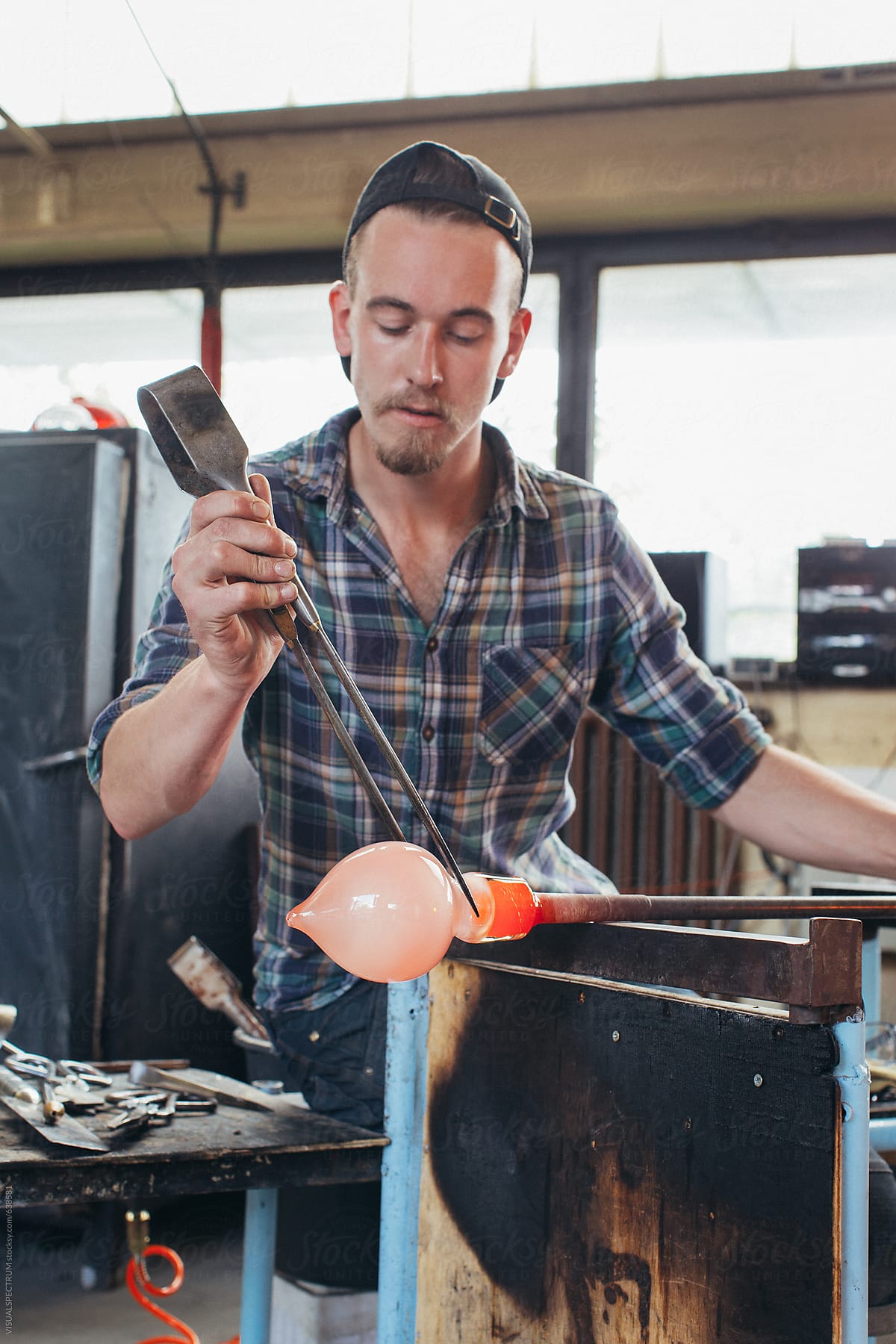Artisan Glass Workshop - Portrait of Young Male Artist Shaping Hot Glass With Jacks