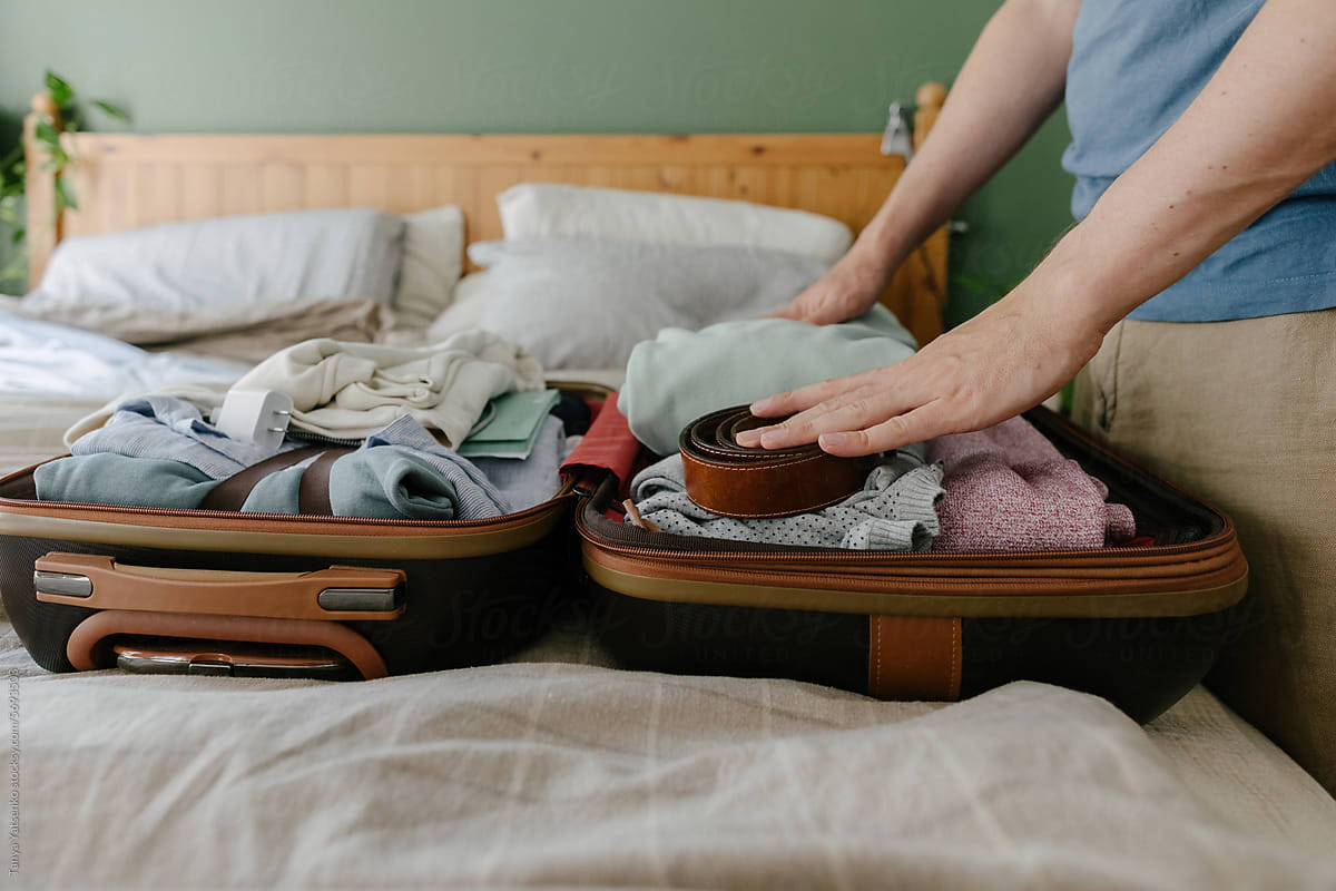 A man packing a suitcase on the bed