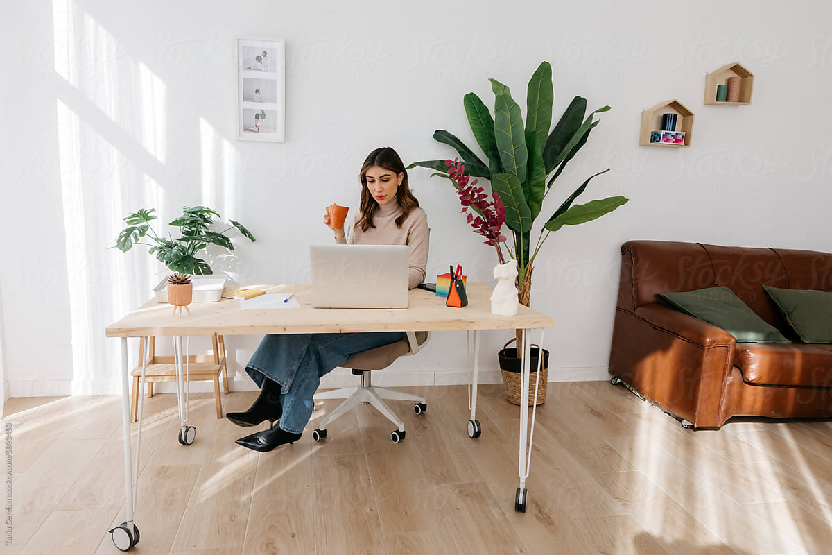 Focused woman drinking from mug during remote work