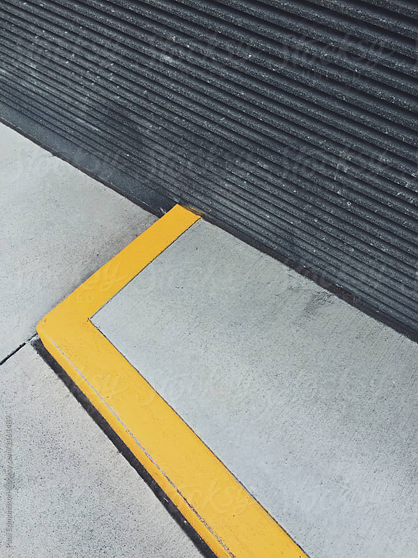 Painted yellow curb and modern building wall, close up