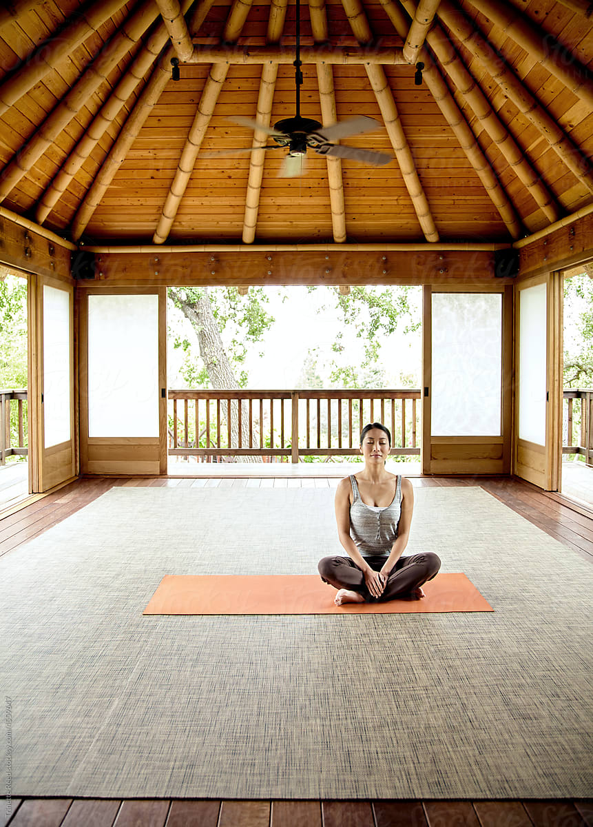 Woman Doing Yoga And Meditating Yoga Inside Of A Yoga Deck by Stocksy  Contributor Trinette Reed - Stocksy