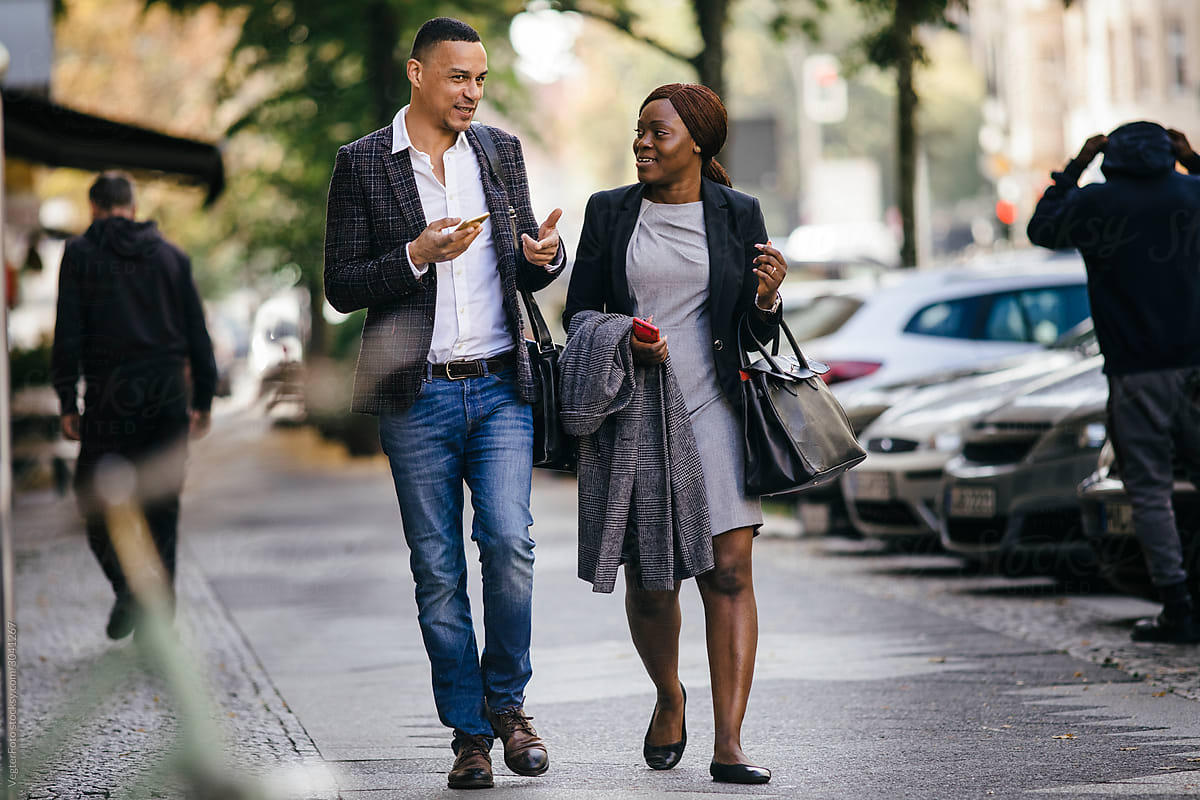 Two Black Business Colleagues Walking Down Street Talking