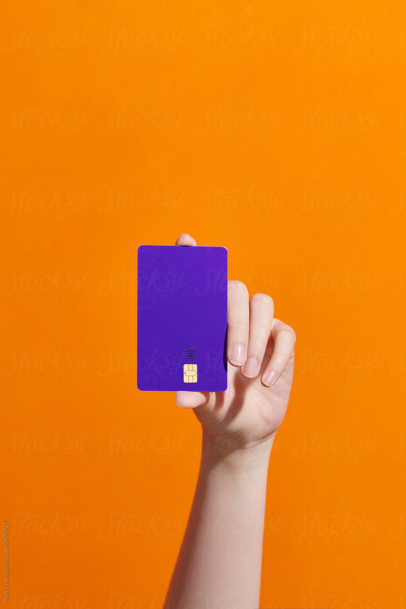 Hand holding credit card on orange background