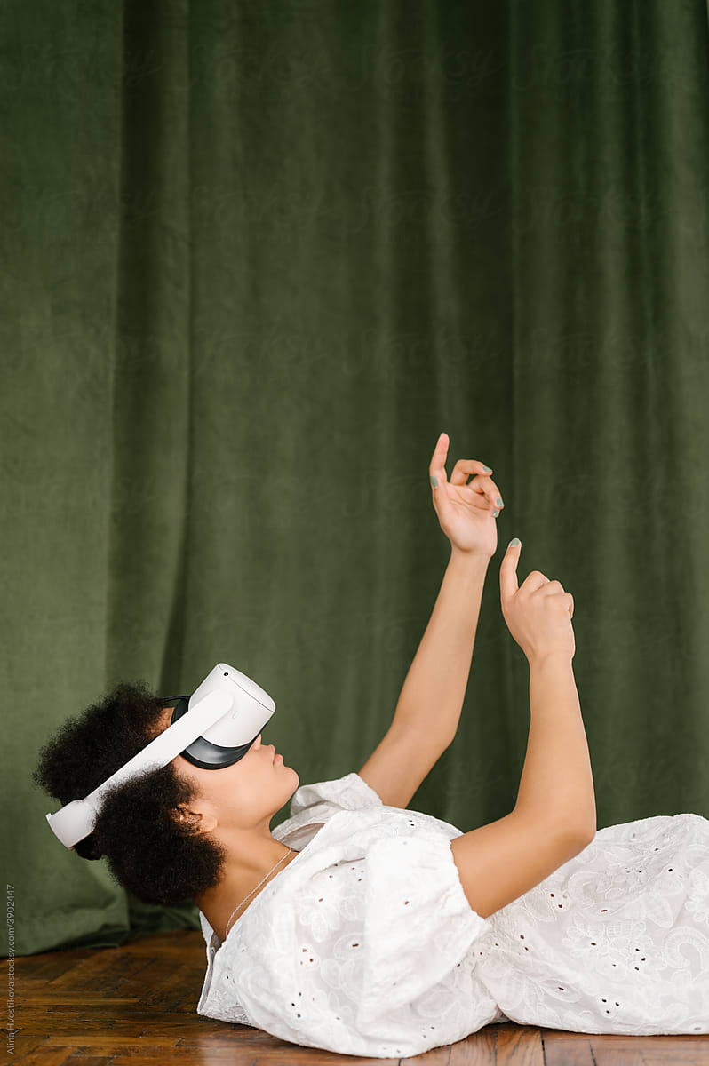 Black female in VR goggles relaxing on floor and gesticulating