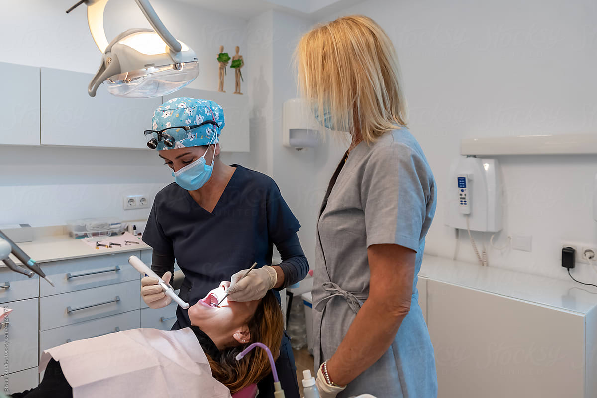 Orthodontist making a dental cleaning to patient with an assistant