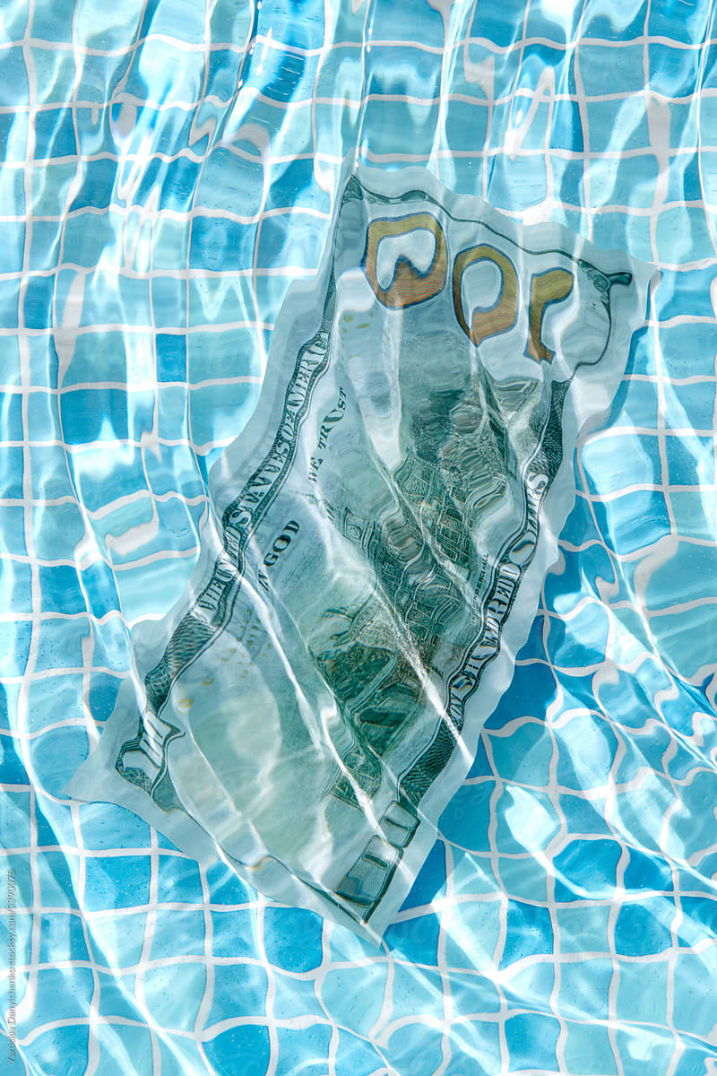 100 dollar banknote floating unrder the water in swimming pool.