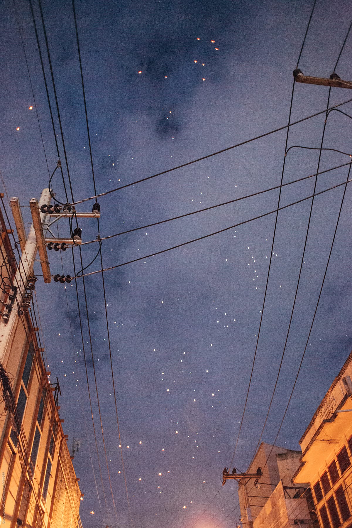 Night time sky and stars with electricity lines and old buildings
