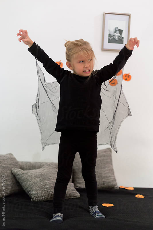 Beautiful little girl dressed as a bat on a Halloween making scary look