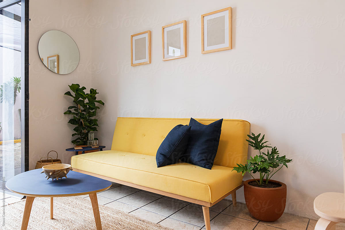 Yellow sofa bed with blue cushions in a living room