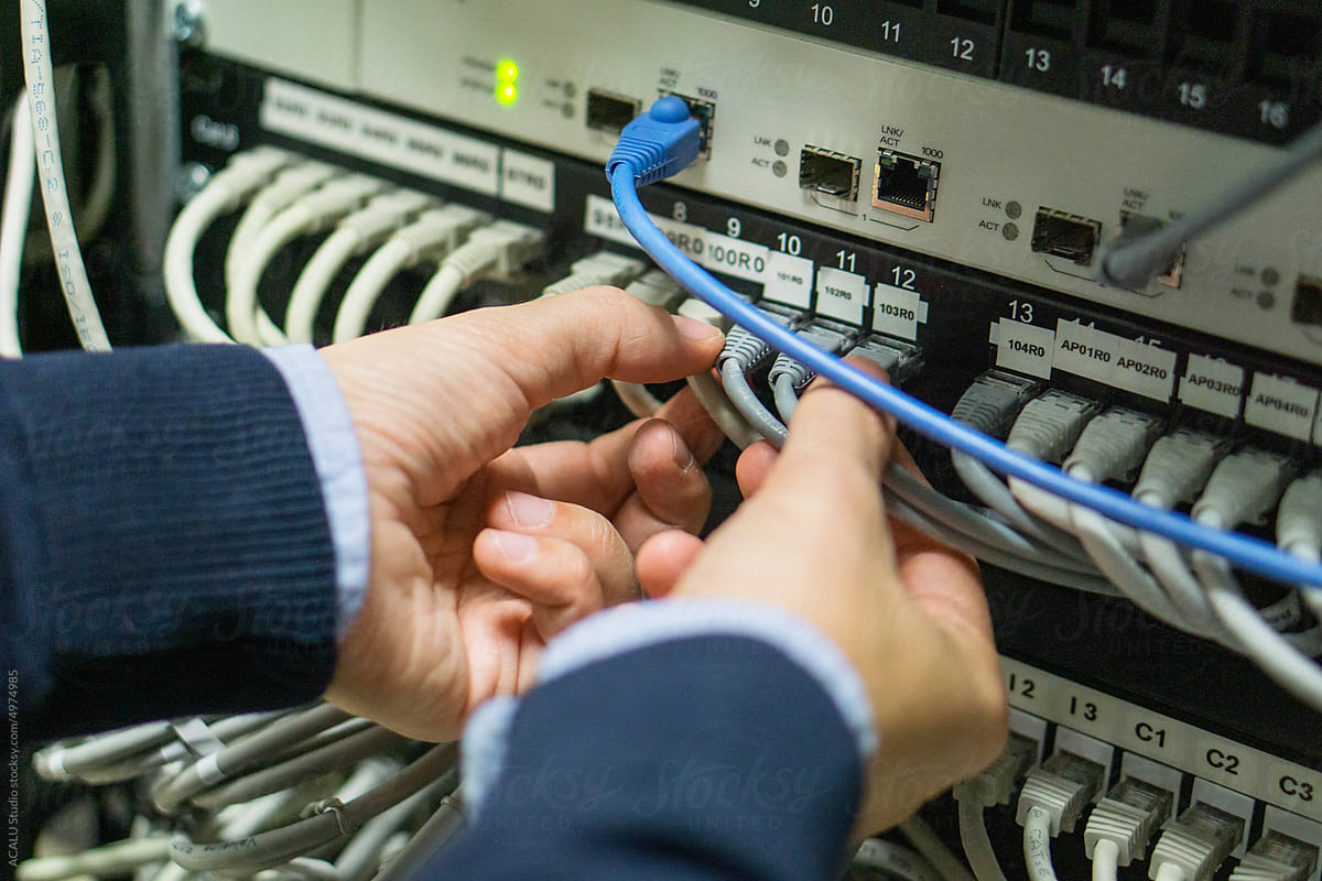 Hands connecting cables in a server rack
