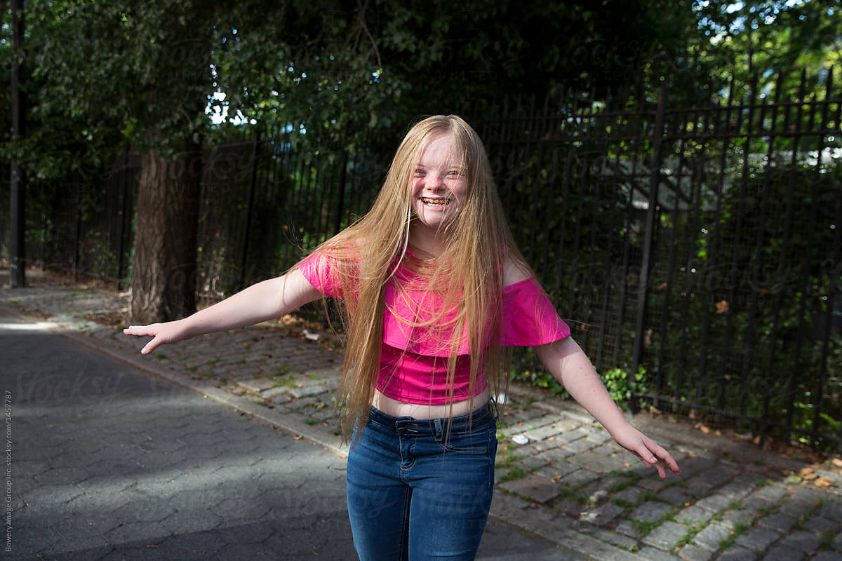 A girl with Down syndrome smiling with long hair. 