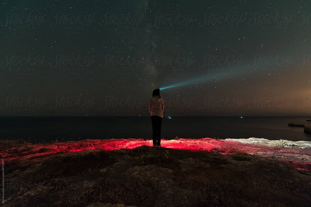 Standing woman with head flashlight looking at the stars