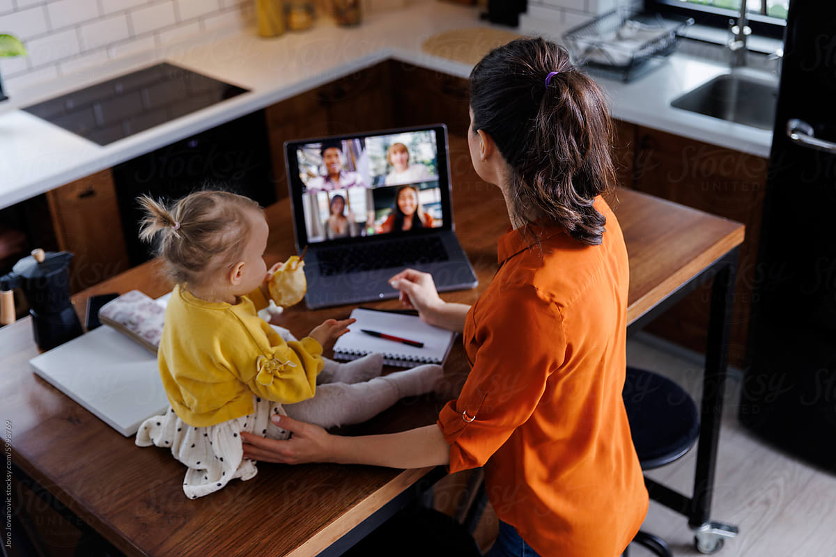 Working mother with daughter during online meeting at home