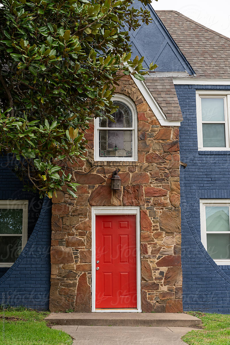 A blue brick house with a red door