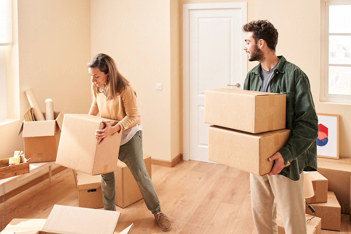 Young man and woman carrying boxes at home