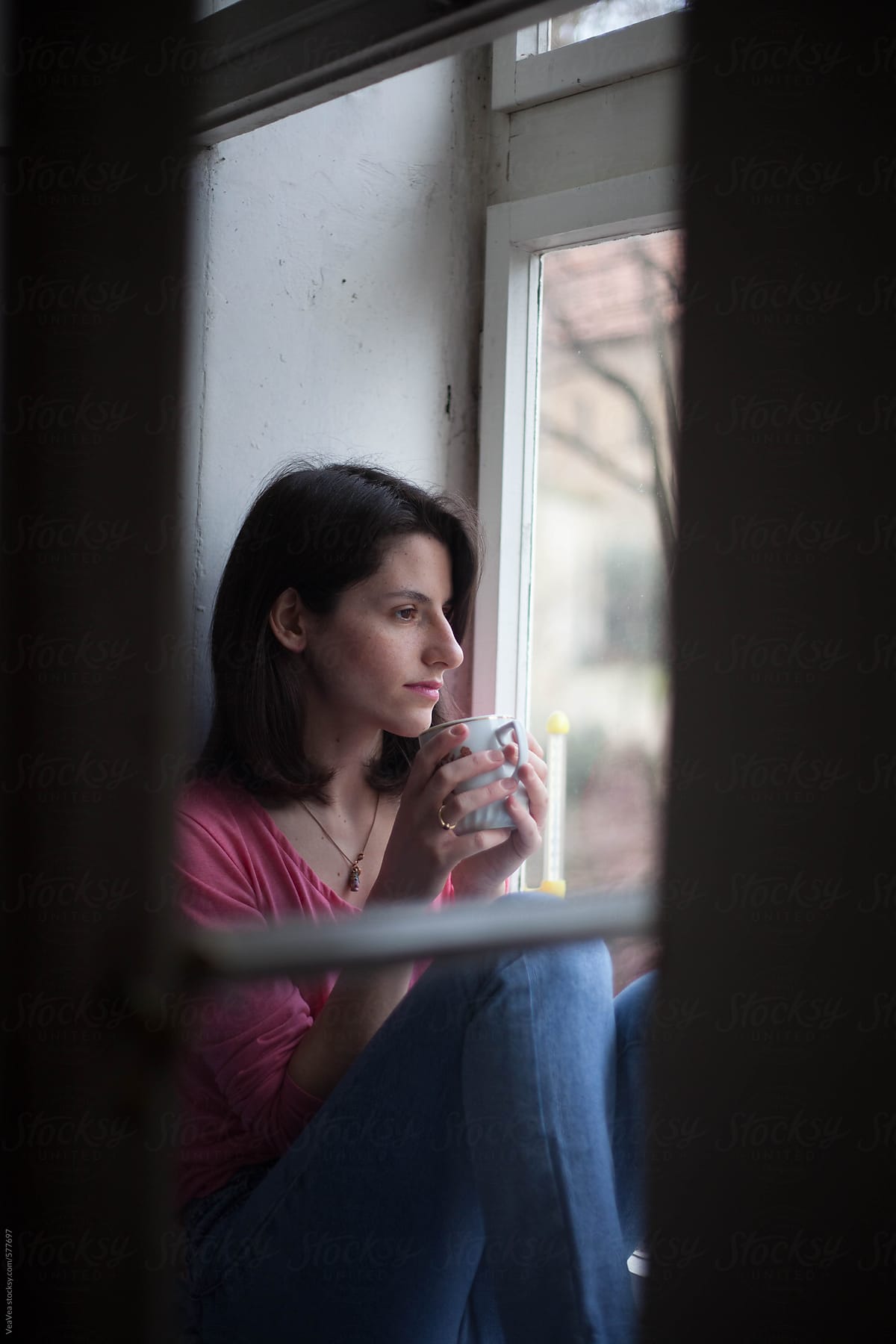 Beautiful woman drinking coffee by the window