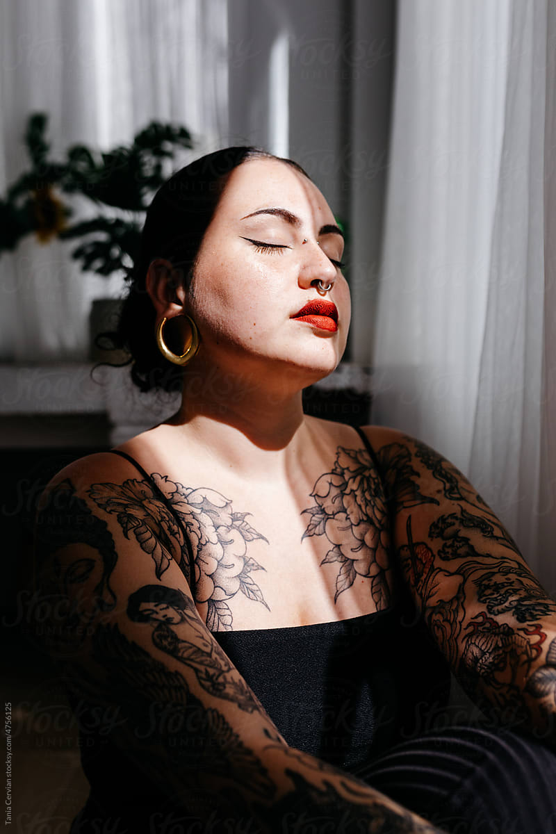 Tattooed woman sitting under sunlight
