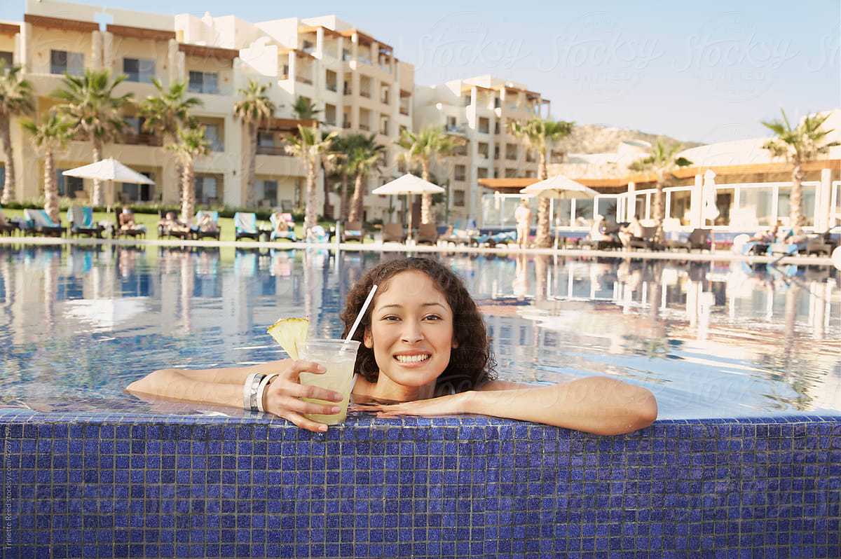 Portrait of woman with drink in pool on vacation
