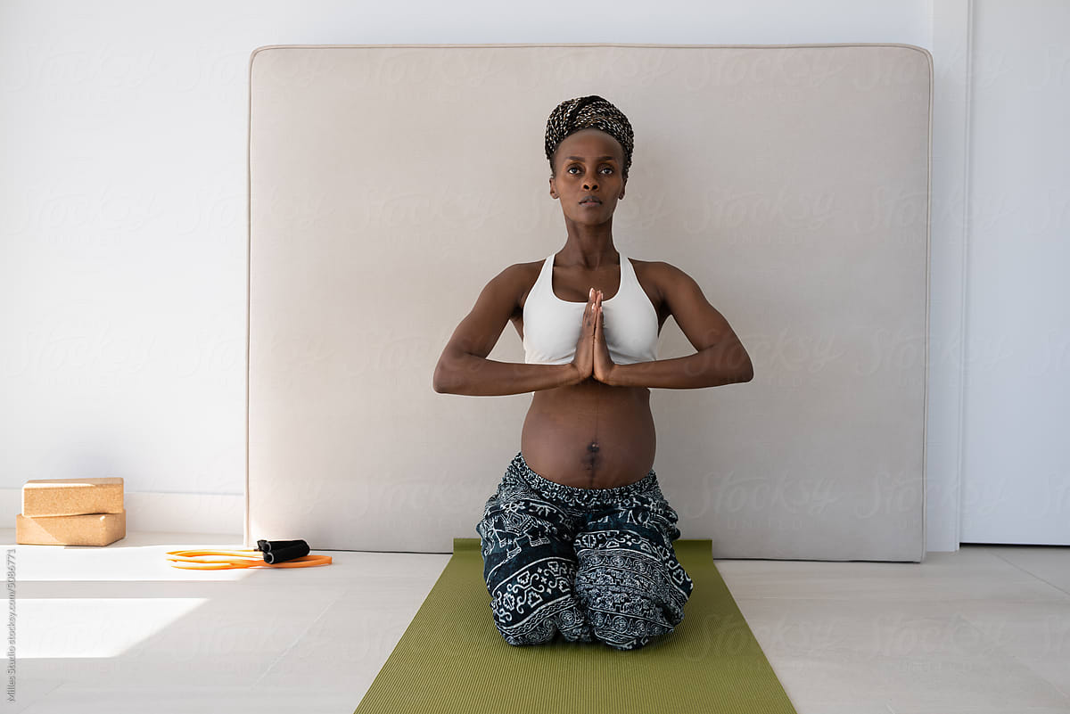 Black pregnant woman meditating in Vajrasana at home