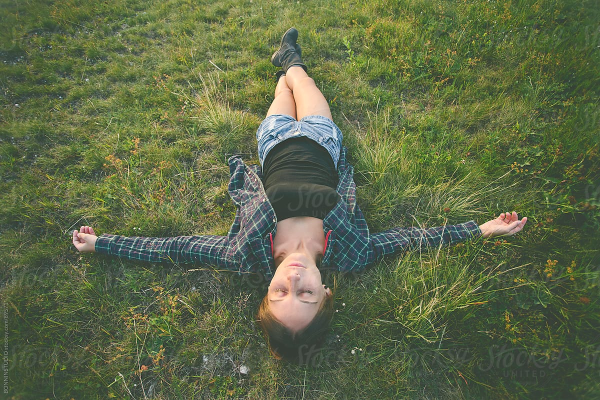 Woman Lying On Green Grass With Stretched Arms And Legs By Stocksy