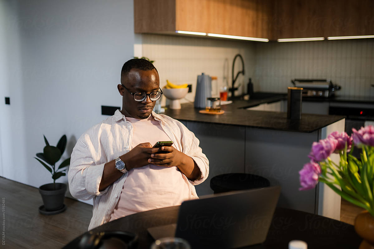 A man uses a mobile phone and laptop at home