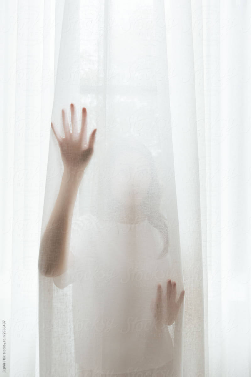 Mysterious portrait of Asian female standing behind soft curtains