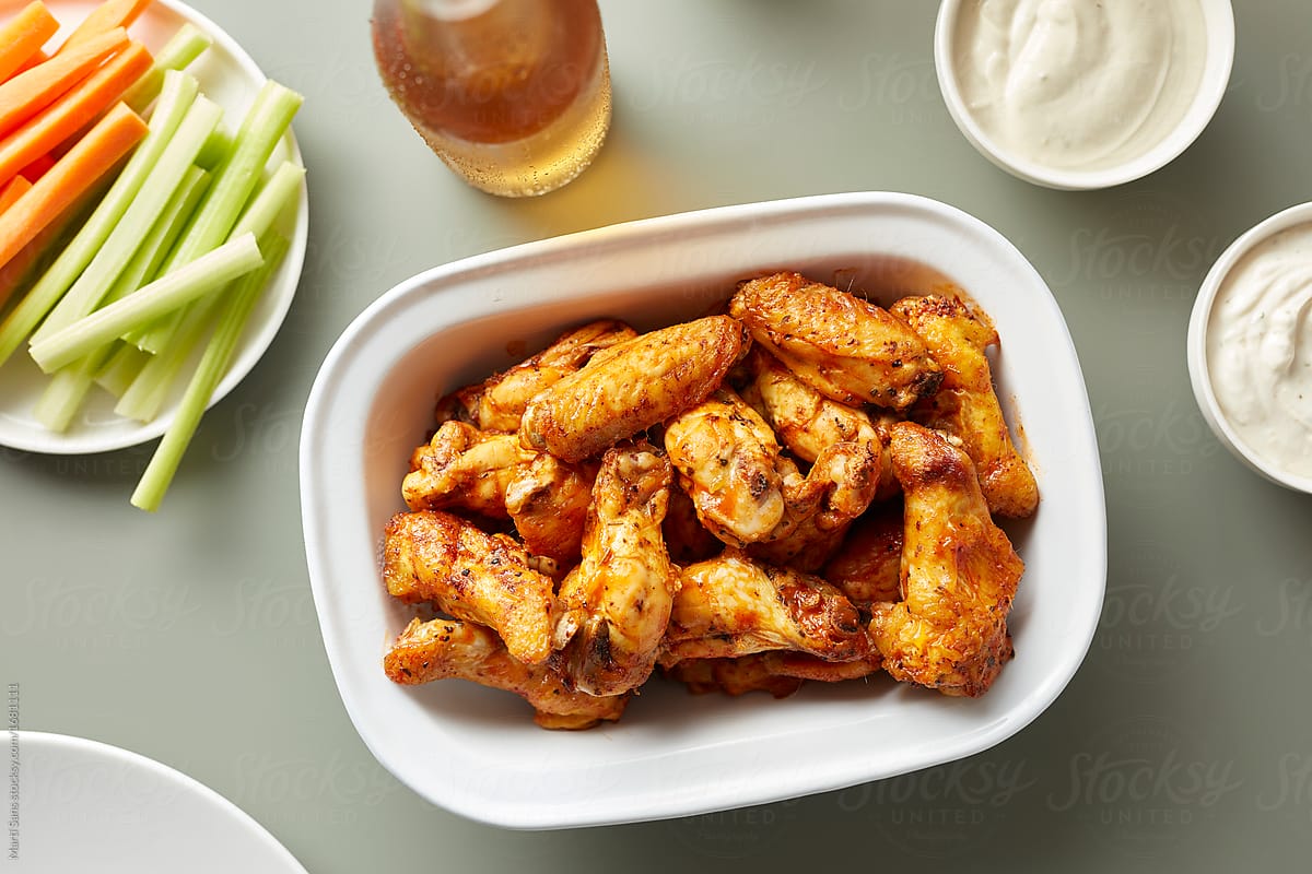 Chicken wings in bowl with beer, carrots and celery
