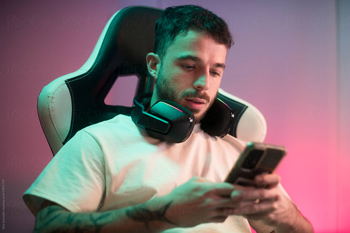 Modern gamer texting on phone during gaming break