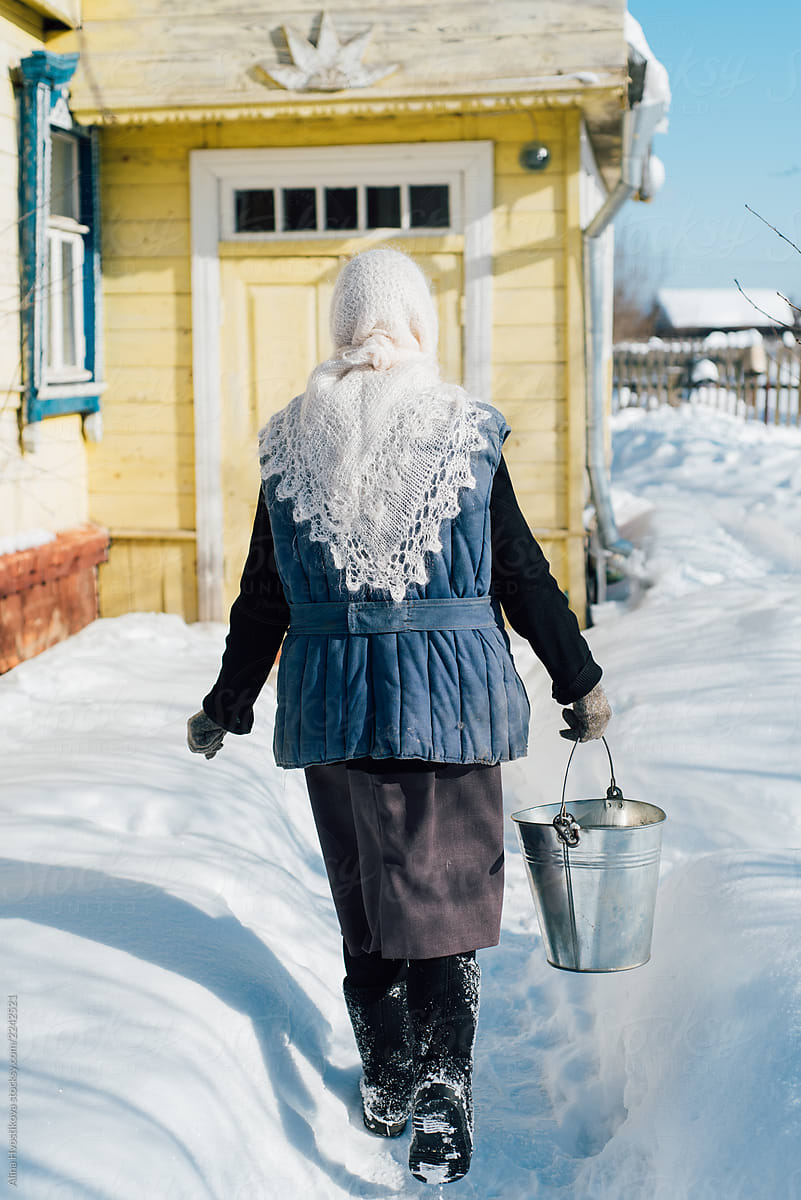 Anonymous woman carrying water in winter