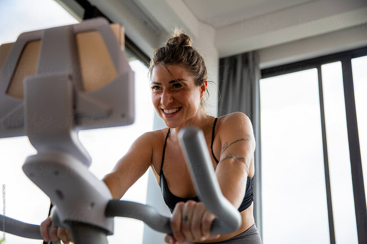 Self-aware empowered Woman smiling while on exercise bike.